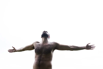 A man standing strong with arms raised in victory, surrounded by soft glowing light and shadows fading.