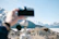 A traveler admiring a breathtaking mountain view with a camera in hand.