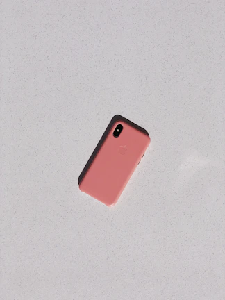 Close-up of a sleek iPhone case in pastel pink resting on a light beige surface.