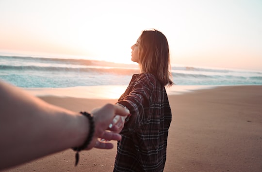 woman holding hands with person facing ocean in La Tranche-sur-Mer France