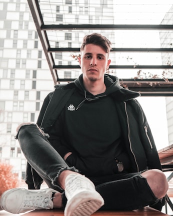 A casual outfit featuring relaxed-fit jeans and a plain grey sweatshirt on a city bench.