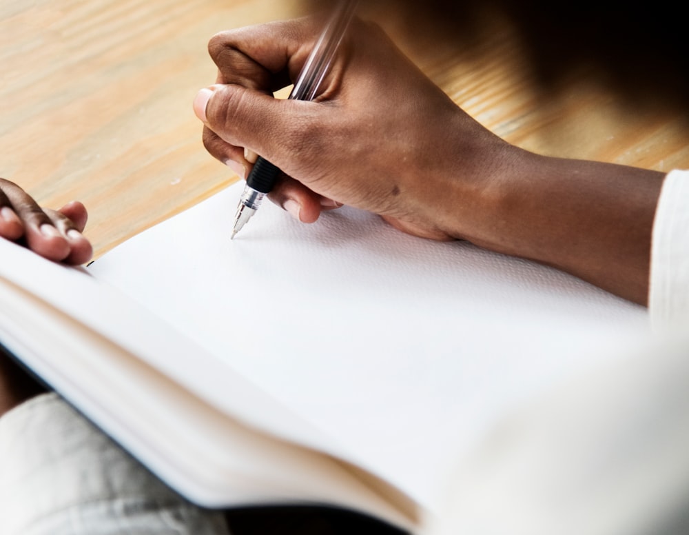 person using black ballpoint pen