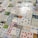 Numerous playing cards and educational number cards are laid out in a patchwork pattern on a surface. The cards are of various styles and designs, including traditional playing cards, cards featuring mathematical equations, and cards with different numerical values and graphics, such as apples, dots, and shapes.