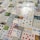 Numerous playing cards and educational number cards are laid out in a patchwork pattern on a surface. The cards are of various styles and designs, including traditional playing cards, cards featuring mathematical equations, and cards with different numerical values and graphics, such as apples, dots, and shapes.