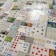 Numerous playing cards and educational number cards are laid out in a patchwork pattern on a surface. The cards are of various styles and designs, including traditional playing cards, cards featuring mathematical equations, and cards with different numerical values and graphics, such as apples, dots, and shapes.