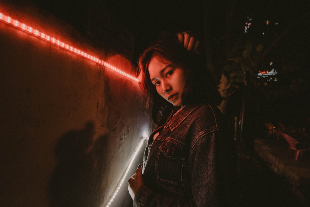 woman wearing blue denim jacket standing beside red LED