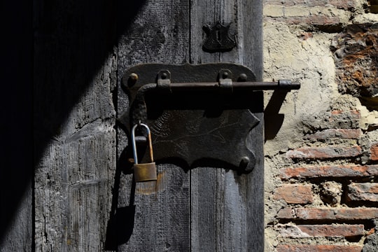 black and brown padlock on black wooden door in Tuscany Italy