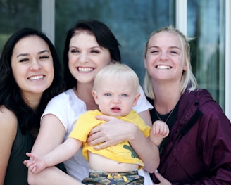 woman carrying baby with two ladies beside her smiling