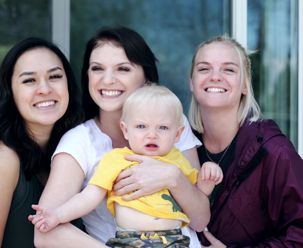 woman carrying baby with two ladies beside her smiling