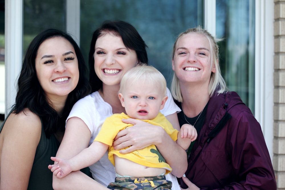 woman carrying baby with two ladies beside her smiling