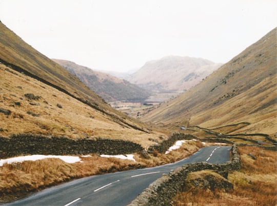 empty long road between mountains in Lake District National Park United Kingdom
