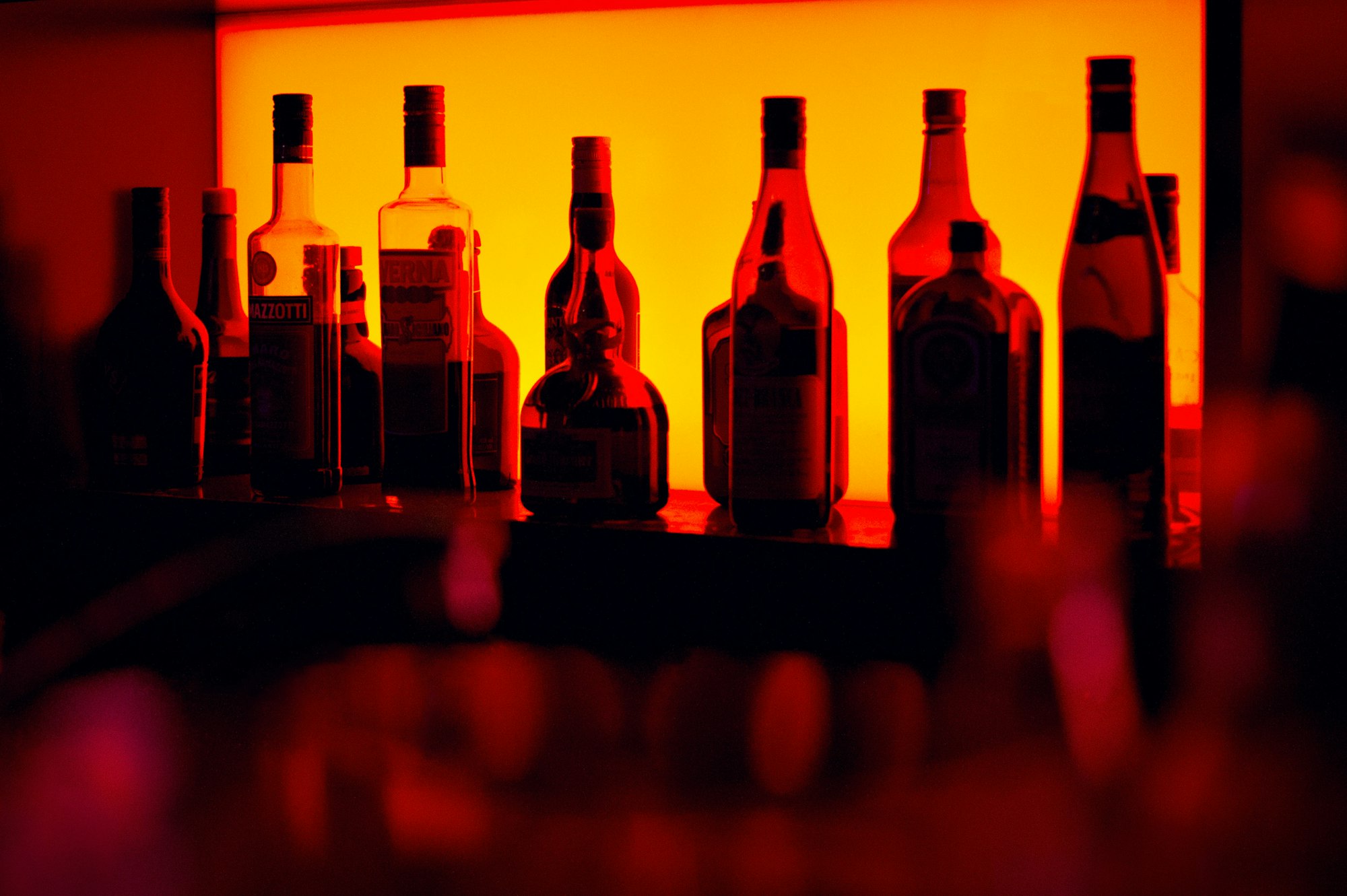 Image of various bottles of alcohol in front of a glowing background at a bar.
