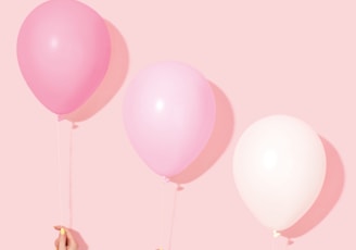 person holding pink and white balloon