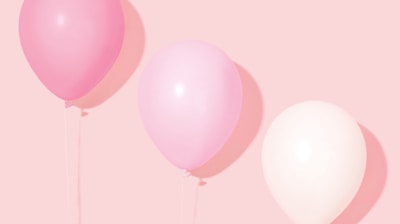 person holding pink and white balloon