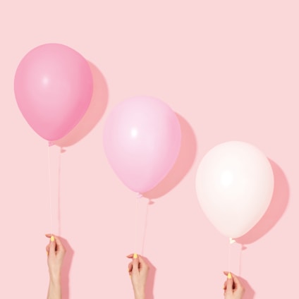 person holding pink and white balloon