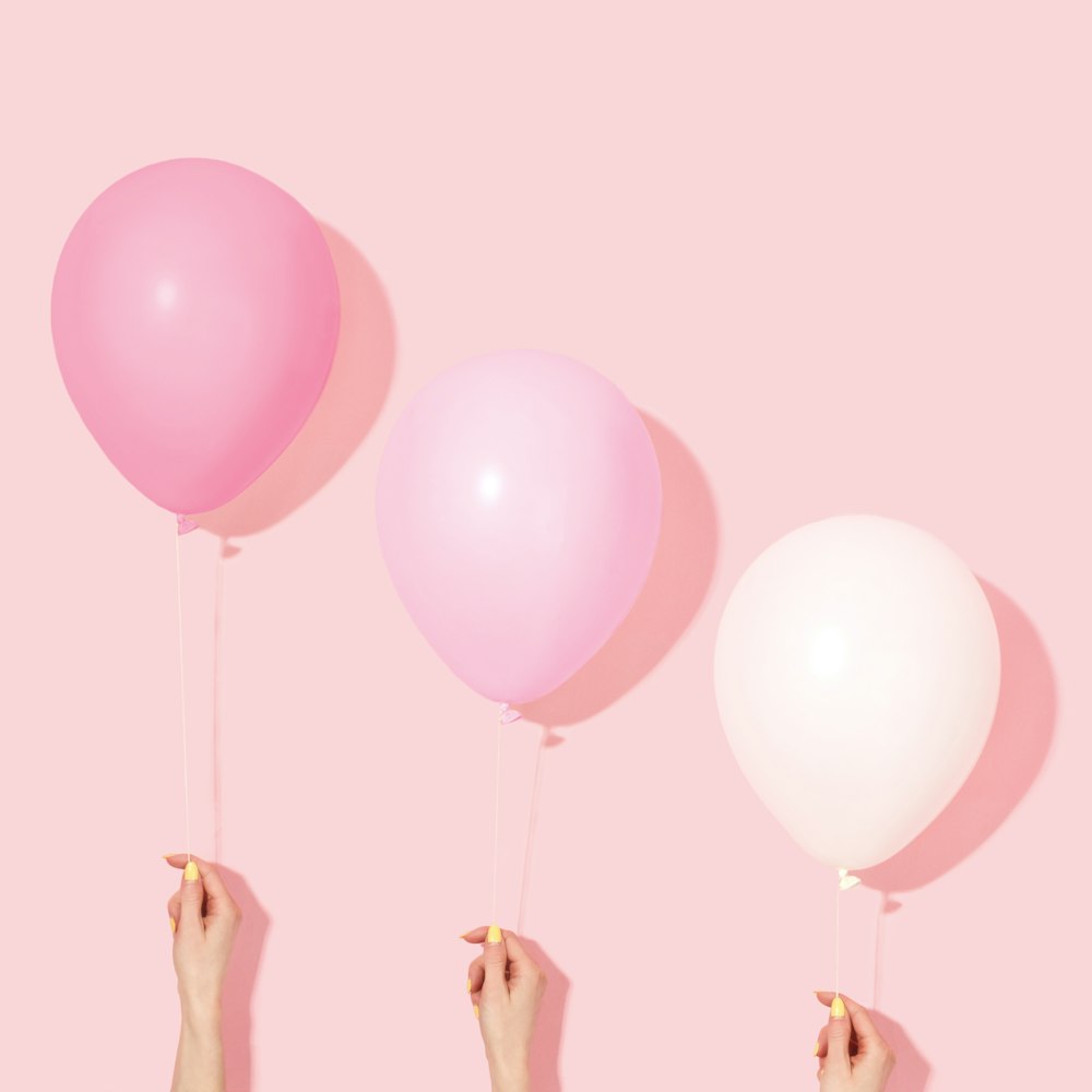pessoa segurando balão rosa e branco