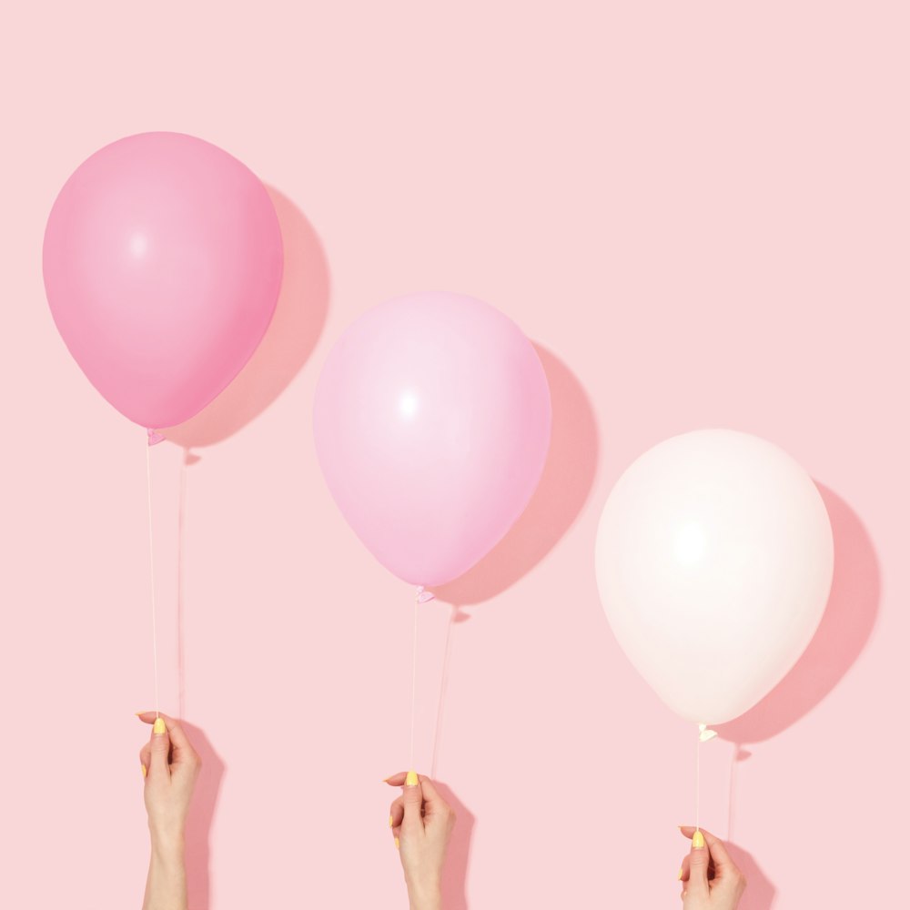 person holding pink and white balloon