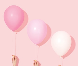 person holding pink and white balloon