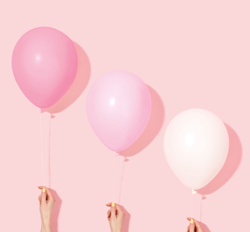 person holding pink and white balloon