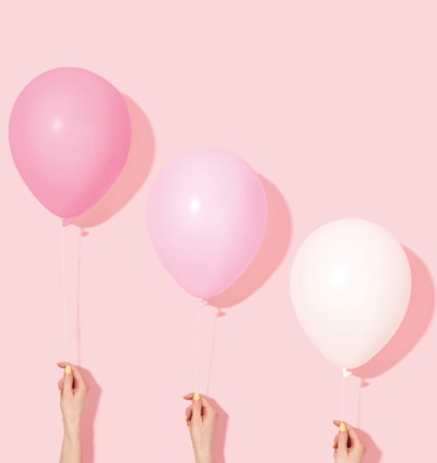 person holding pink and white balloon