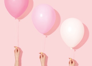 person holding pink and white balloon