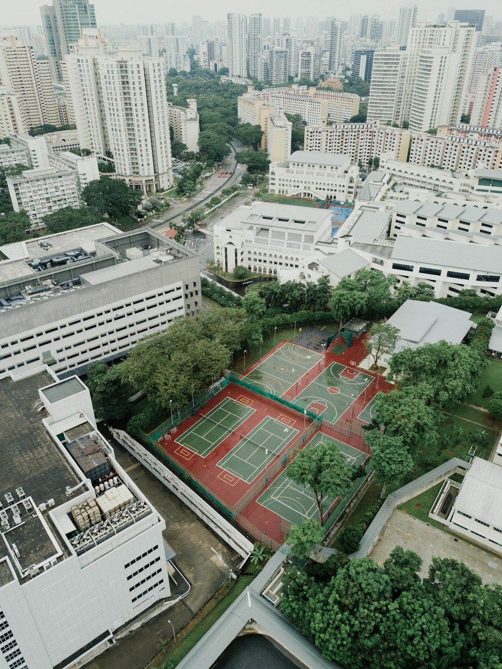aerial photography of basketball and tennis court in the middle of high-rise buildings
