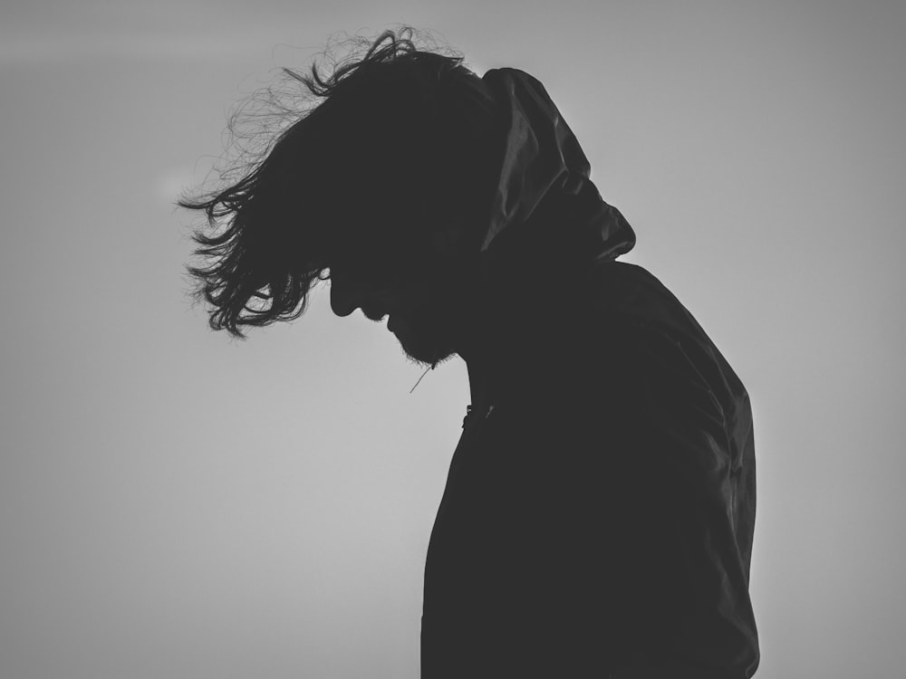 silhouette of man wearing hoodie looking down