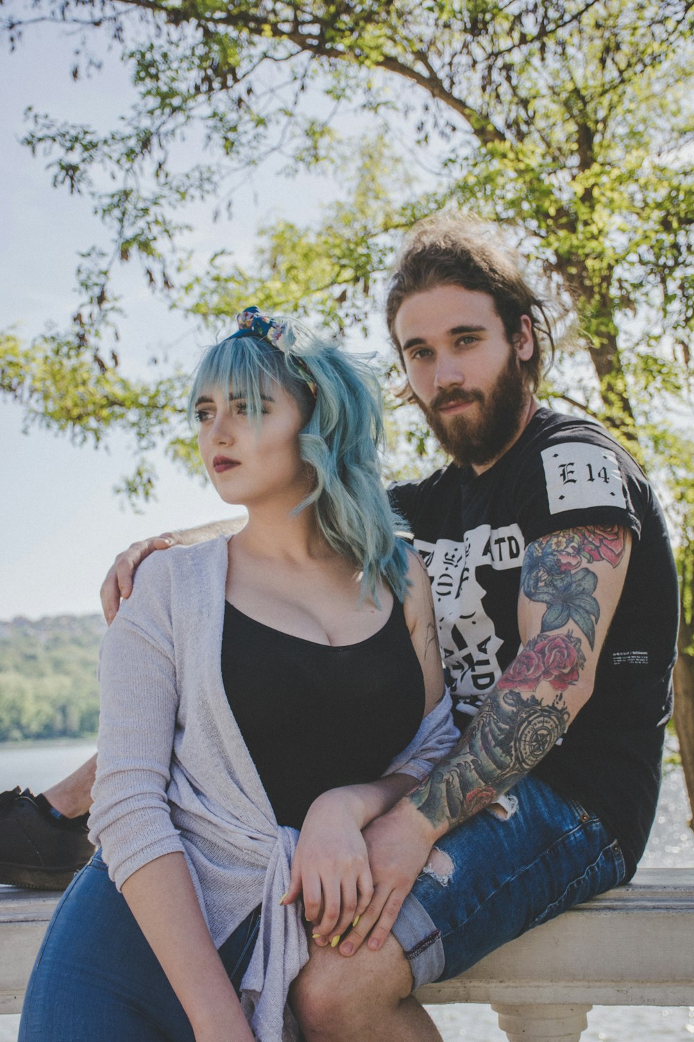 woman leaning to a man sitting on fence during daytime