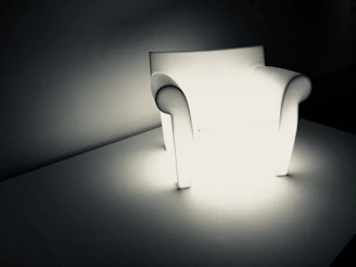 A futuristic smart relaxation chair glowing subtly in a dimly lit room with parallax effects enhancing its contours.