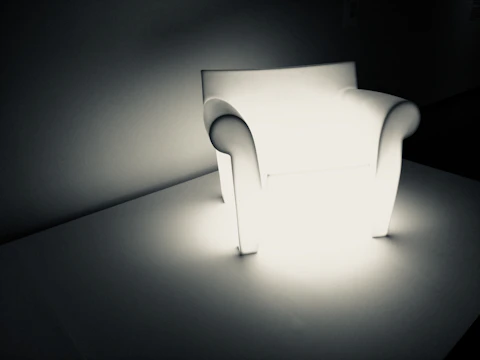 A futuristic smart relaxation chair glowing subtly in a dimly lit room with parallax effects enhancing its contours.