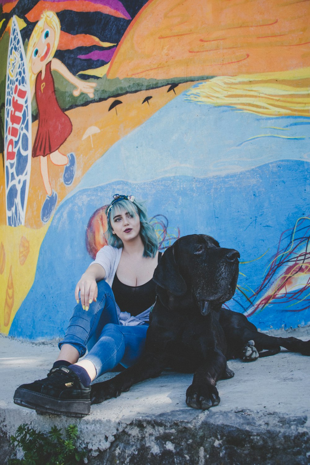 woman sitting beside dog leaning on wall