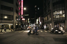 A bustling city street at night with colorful neon signs and blurred motion of people.