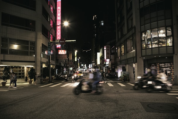 A bustling city street at night with colorful neon signs and blurred motion of pedestrians.