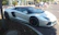 A sleek luxury sports car parked on a sunlit city street, reflecting the vibrant urban atmosphere.