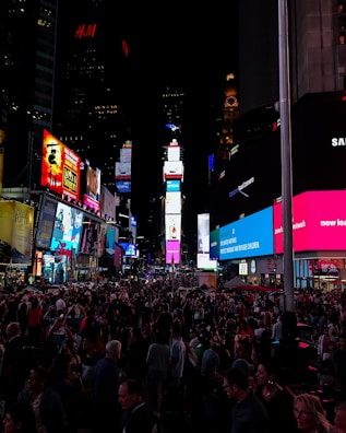 A bright LED billboard displaying colorful advertisements at night in a busy city square.