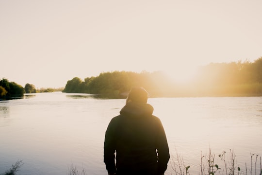 sepia tone photo of man standing in front of body of water in Teodoro Schmidt Chile