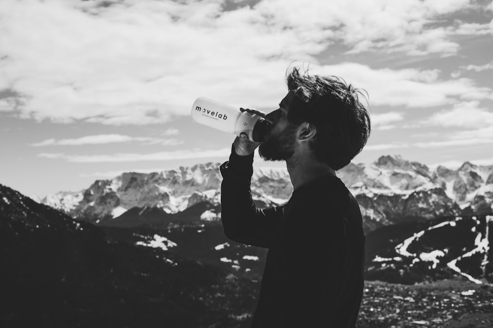 man drinking water on top of mountian