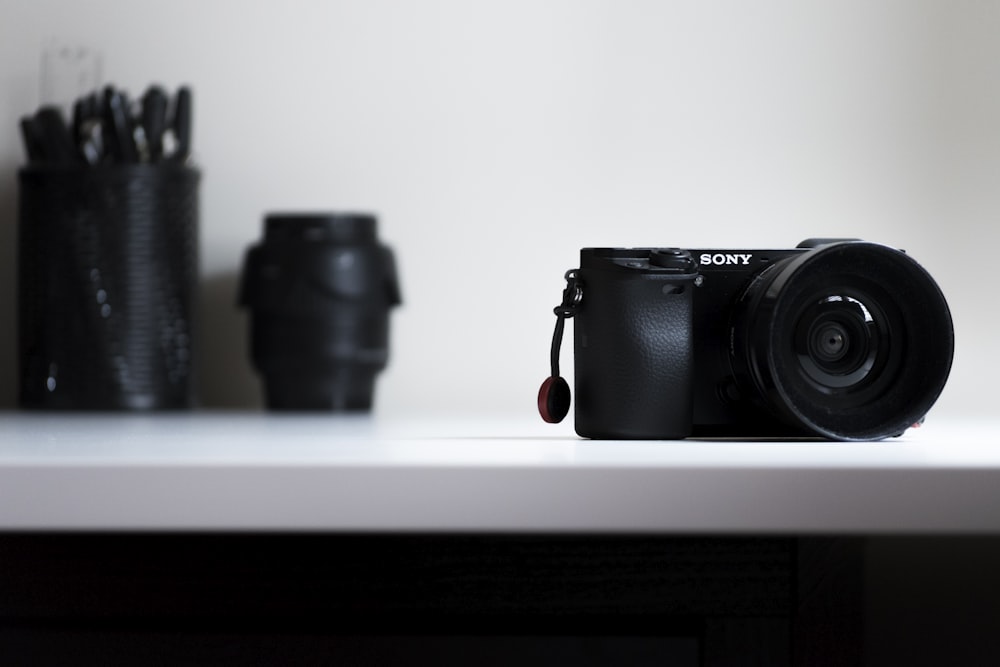 black Sony DSLR camera on white desk