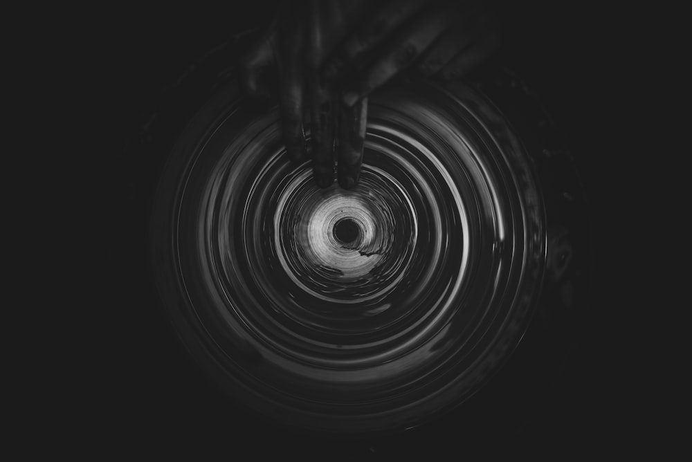 Foto en escala de grises de una persona haciendo una vasija de barro