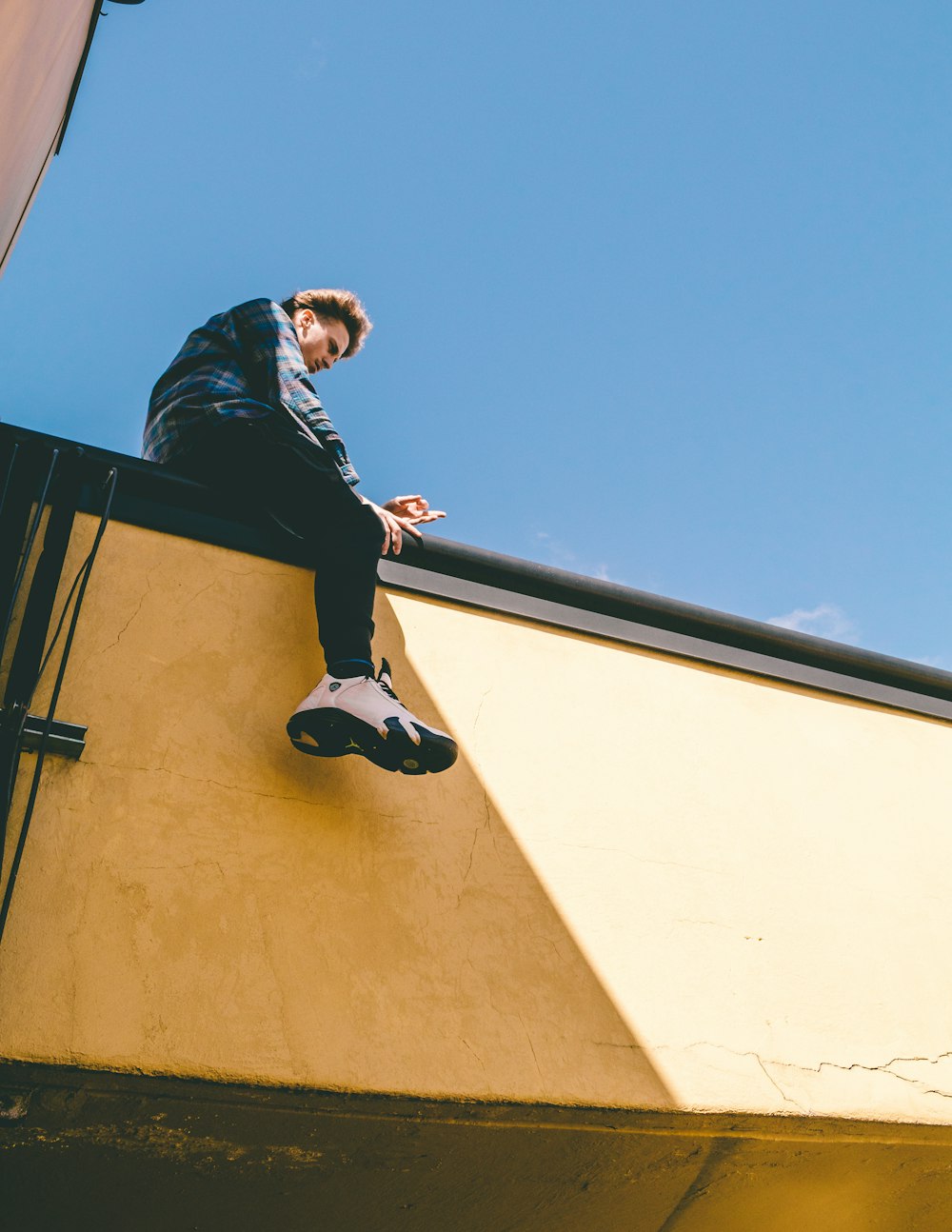 man sitting on roof under blue sky