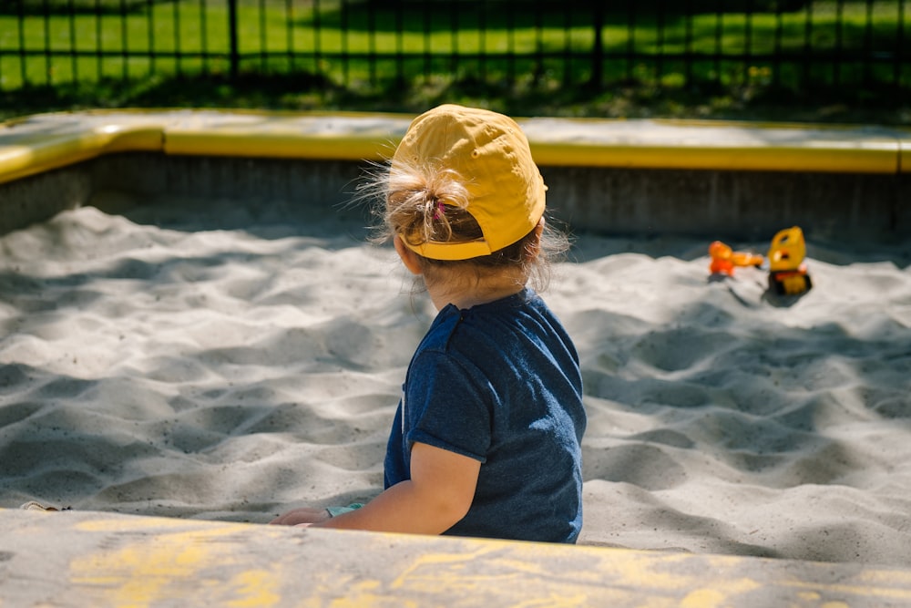 Mädchen spielt auf Sandkasten