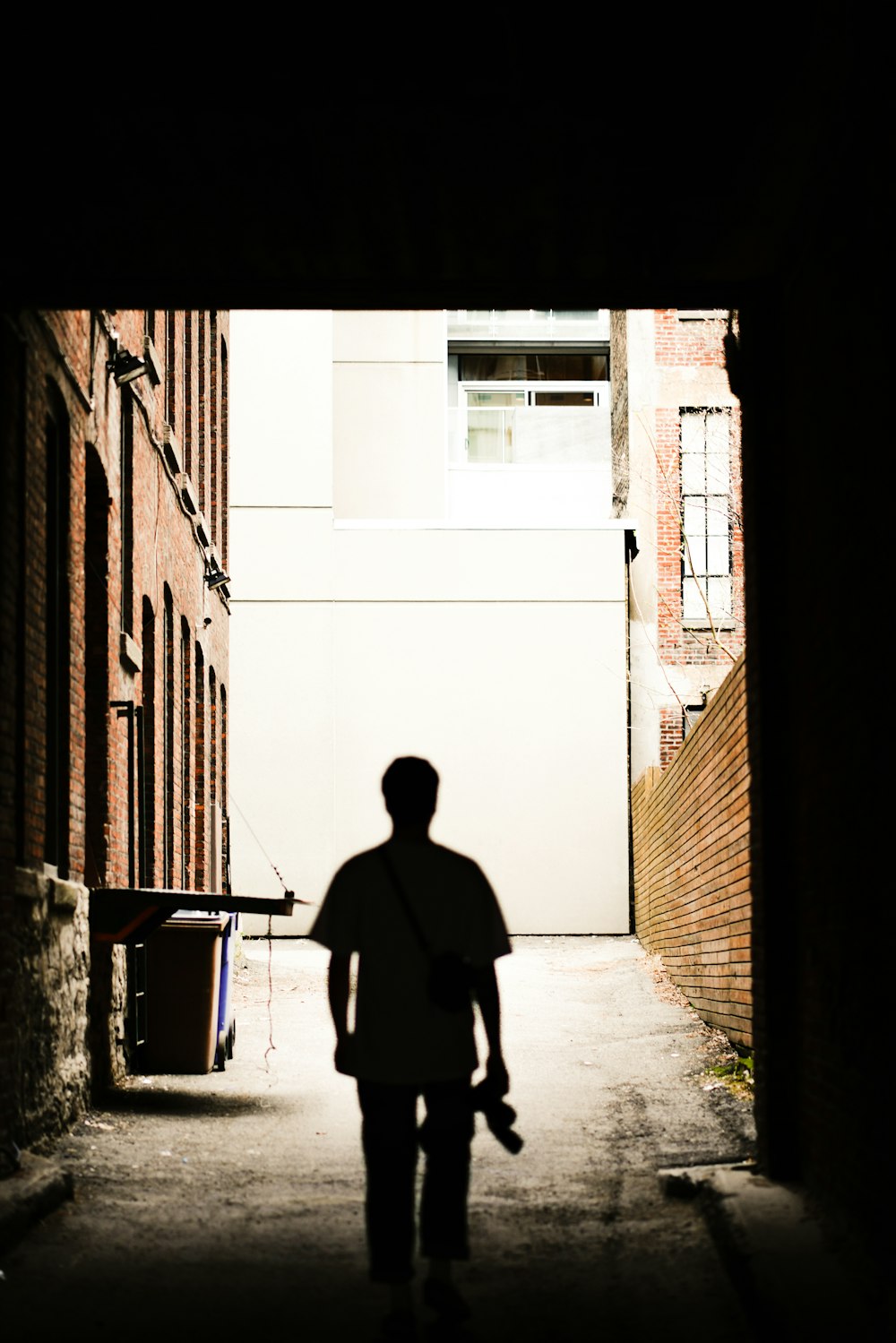 silhouette photography of man holding camera standing in front of wall