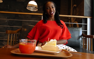 A cheerful young woman enjoying a colorful juice at a sleek, modern café table.