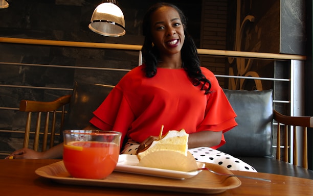 A cheerful young woman enjoying a colorful juice at a sleek, modern café table.