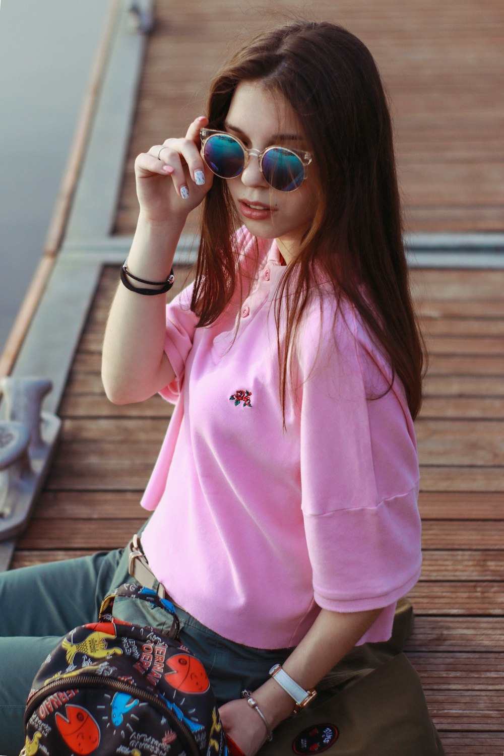 woman sitting at the dock holding her sunglasses