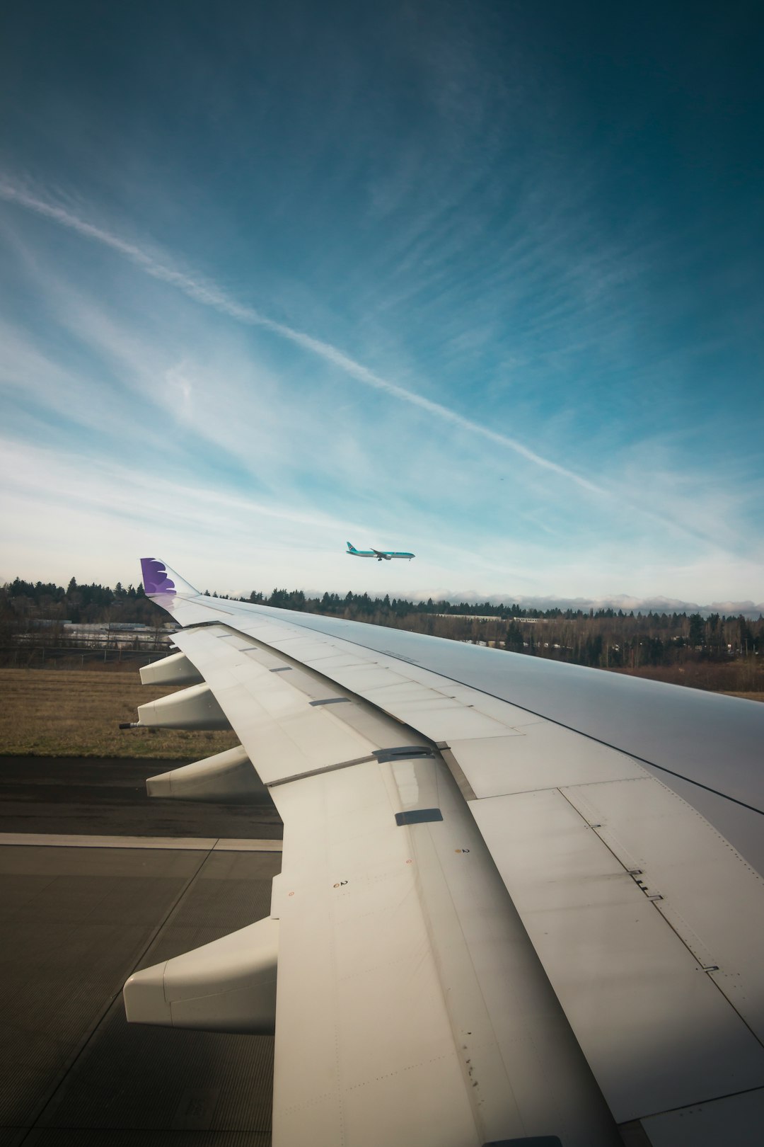 airplane wing under blue and white sky