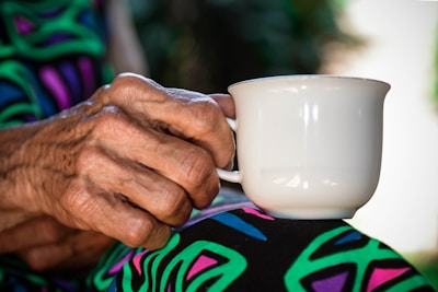 Close-up of a hand holding a ceramic mug with an artistic pattern.