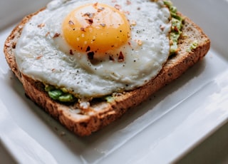 bread with sunny side-up egg served on white ceramic plate