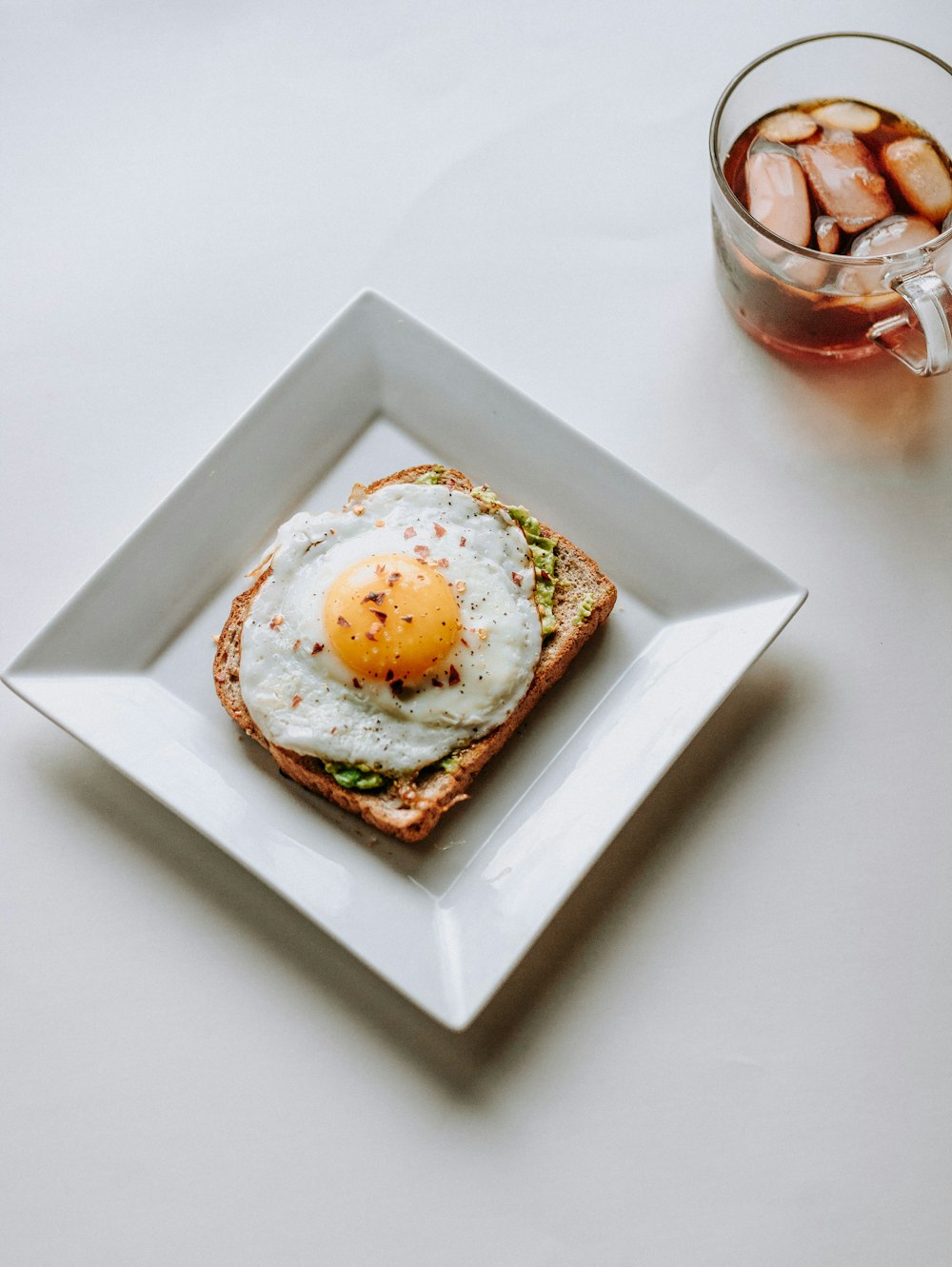 Plato de cerámica de clara de huevo frita junto a taza de vidrio