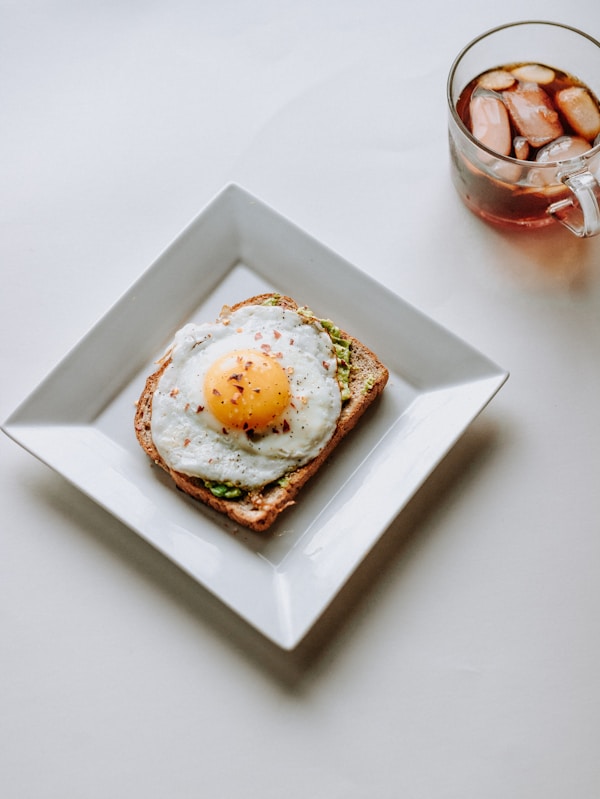 Fried egg white ceramic plate beside glass mug